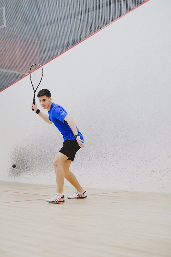 Focused athlete playing squash in an indoor court, showcasing precision and skill.